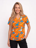 A smiling blonde woman wearing a short-sleeve V-neck scrub top with a colorful dinosaur pattern on an orange background, paired with black pants, against a plain white studio background.
Dinosaur printed orange medical scrub top for women, pediatric nursing uniform