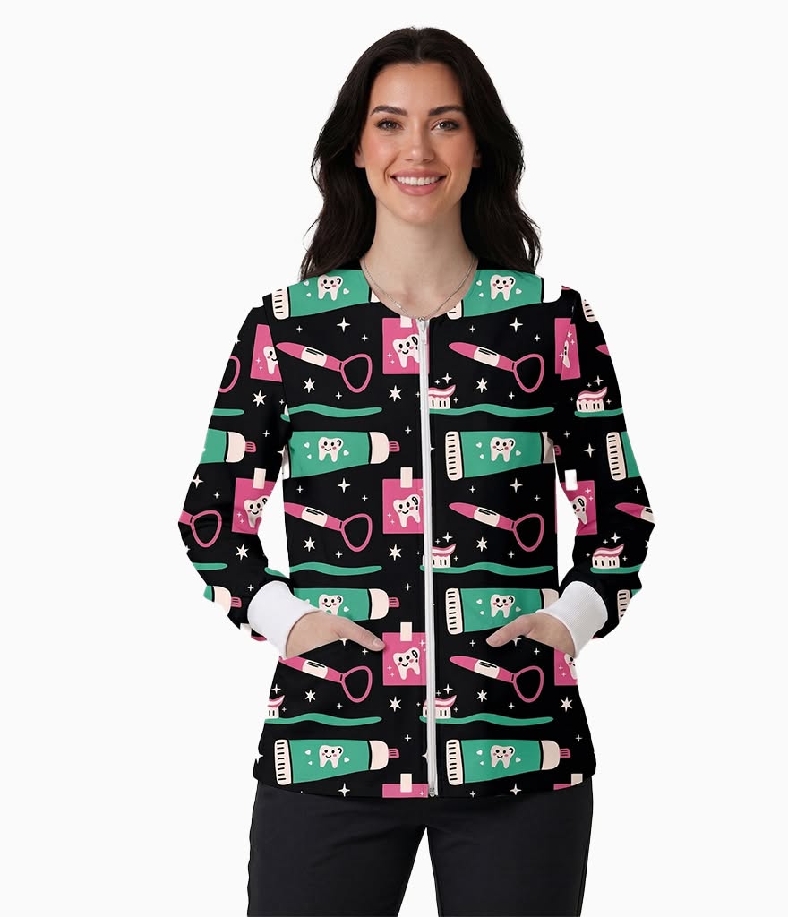 A woman modeling a black zip-front jacket with a colorful cartoon pattern of toothbrushes, toothpaste tubes, and dental tools on a white studio background.