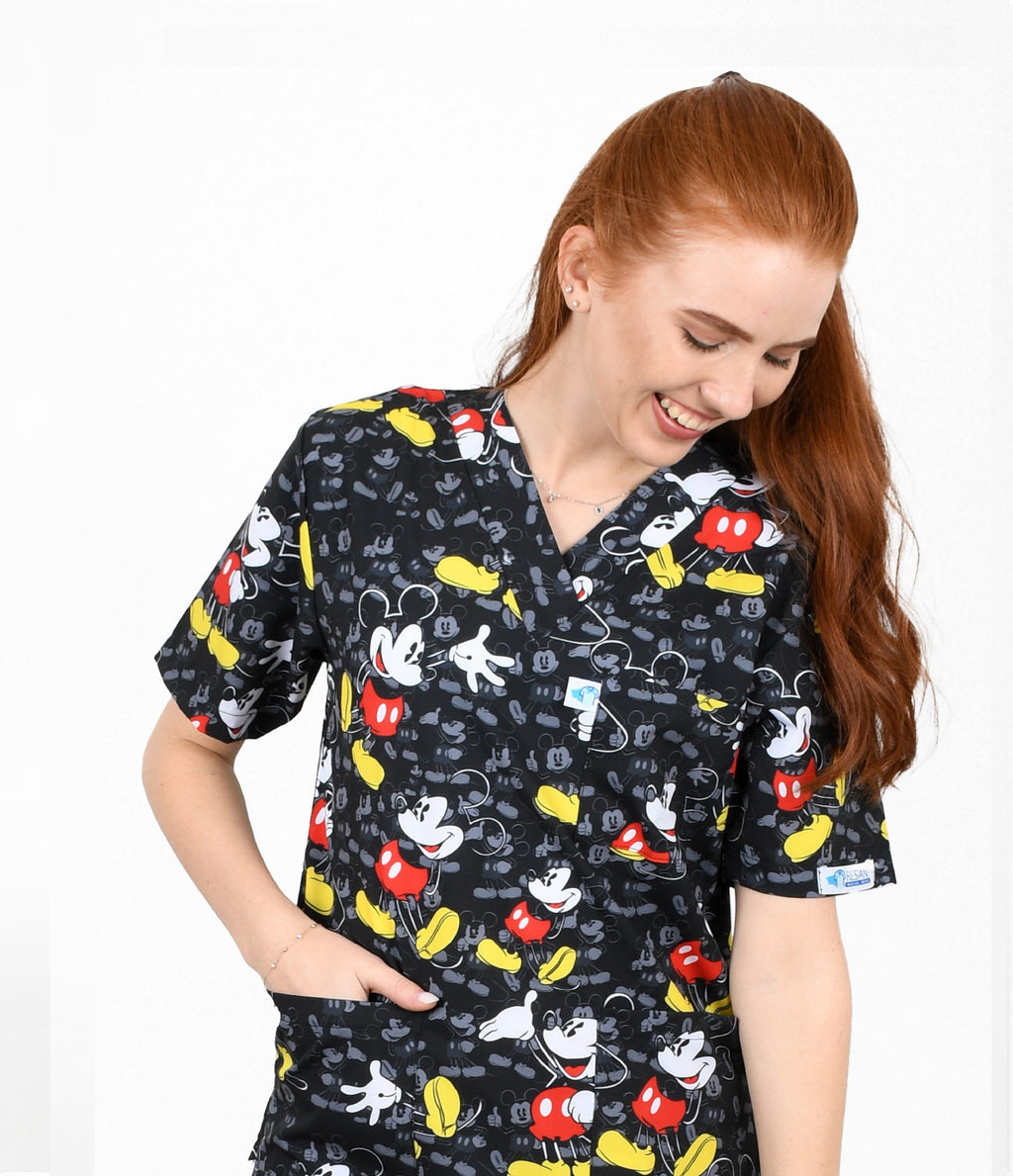 Female healthcare worker wearing black cartoon mouse printed medical scrub top with front pockets.
