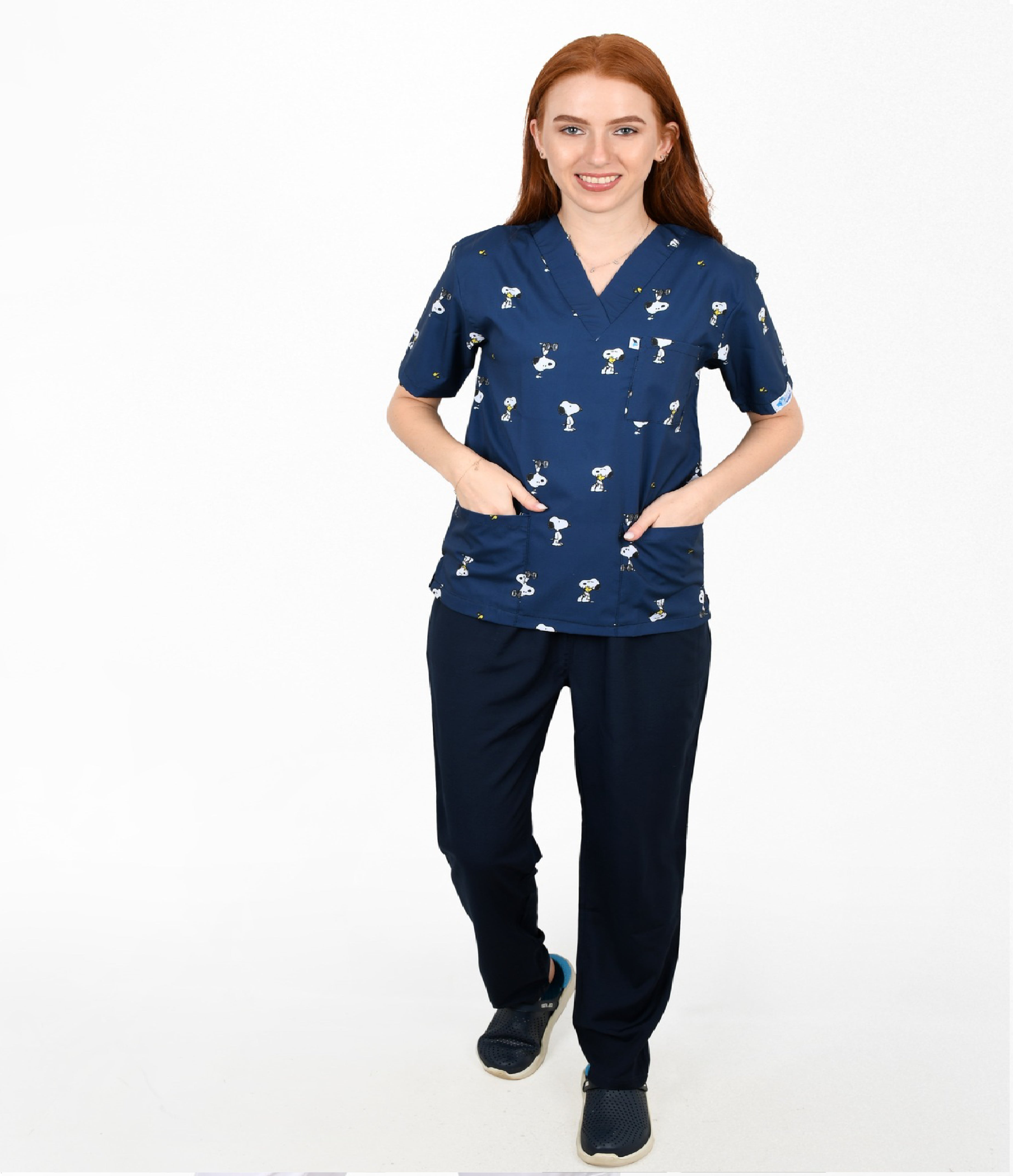 Woman wearing a navy blue scrub set with white patterns on a white background