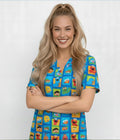Smiling female healthcare worker wearing blue scrub top with colorful cartoon character print in square pattern.
