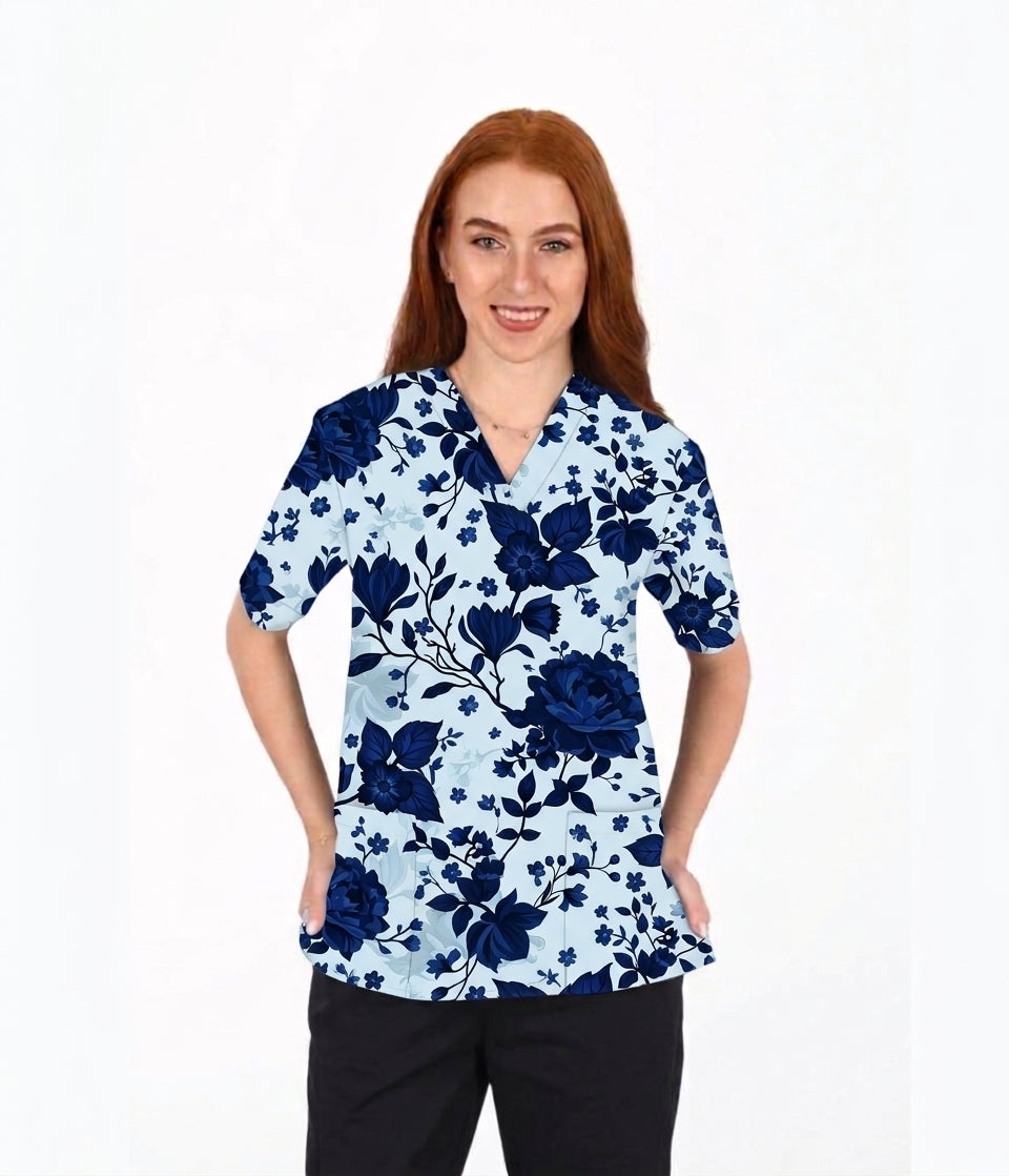 A woman with red hair wearing a light blue and navy blue floral print scrub top, paired with black pants, standing against a plain white background.