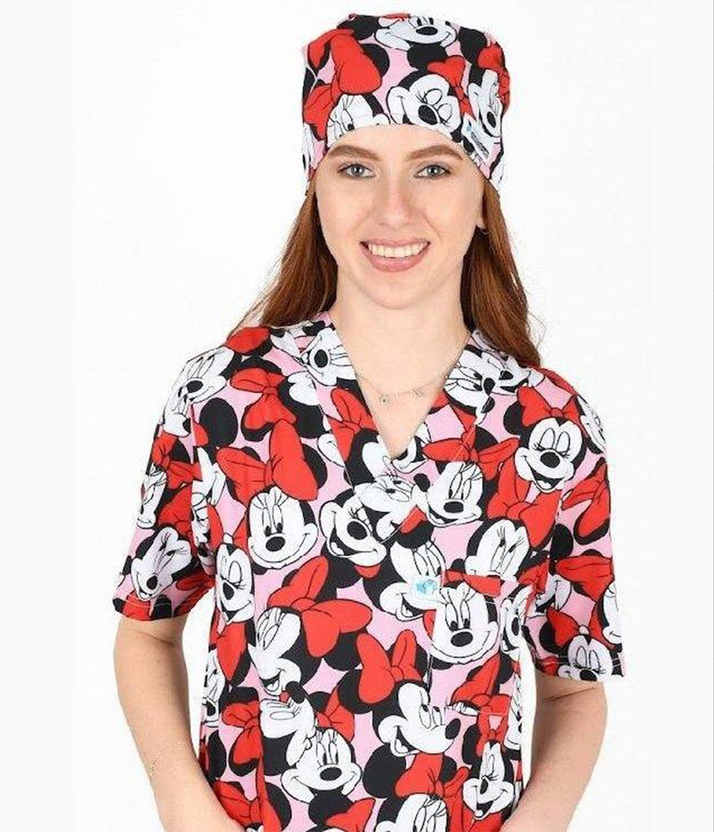 Person wearing a Minnie Mouse-themed scrub top and cap on a white background